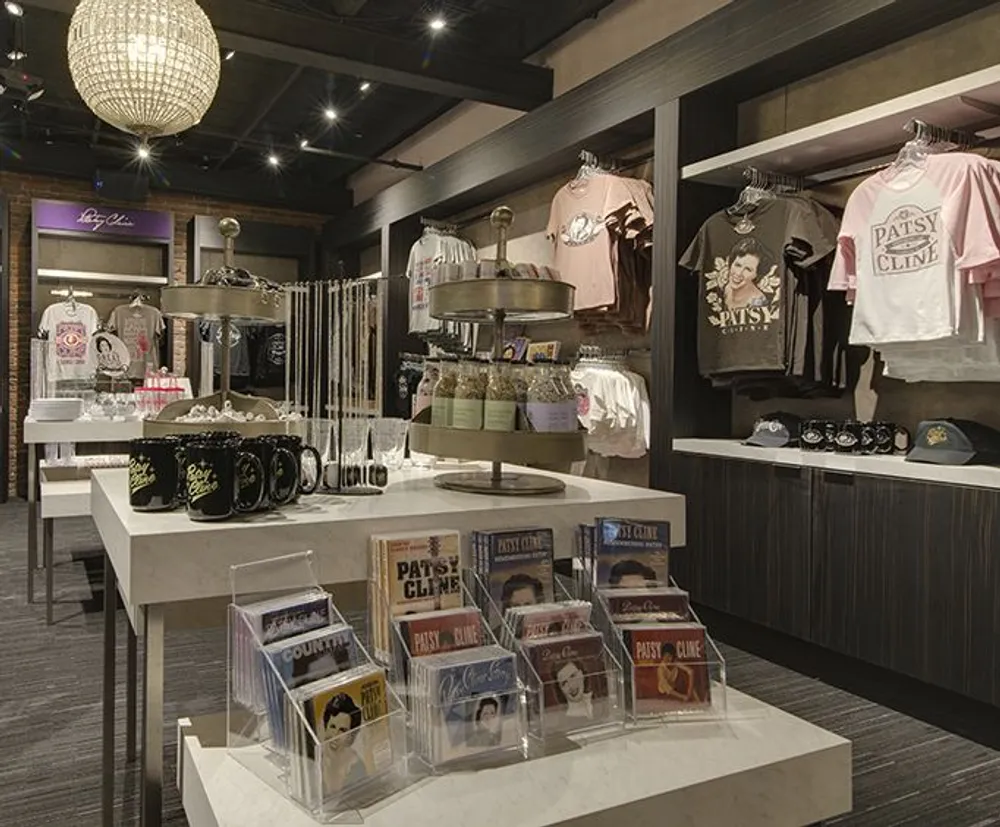 The image depicts the interior of a merchandise store with various items on display including apparel CDs and accessories all themed around a specific personality or brand