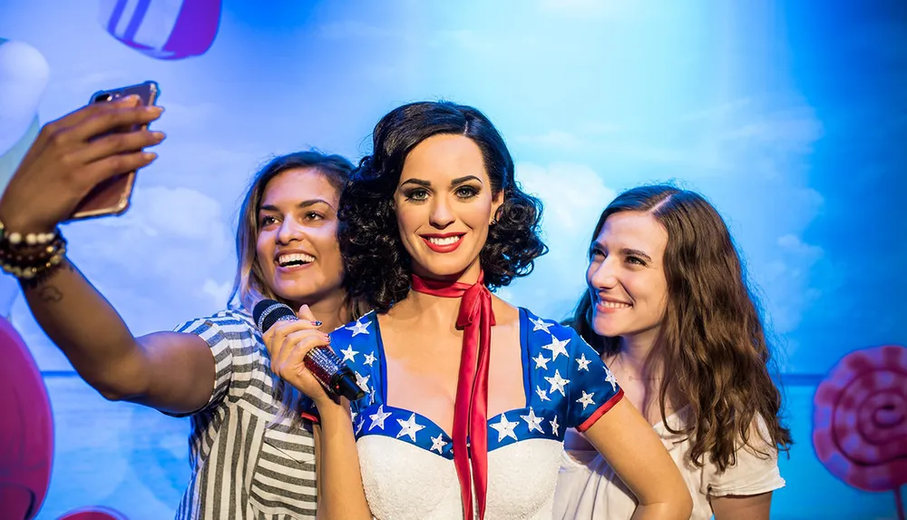 Two people are posing for a selfie with a celebrity wax figure