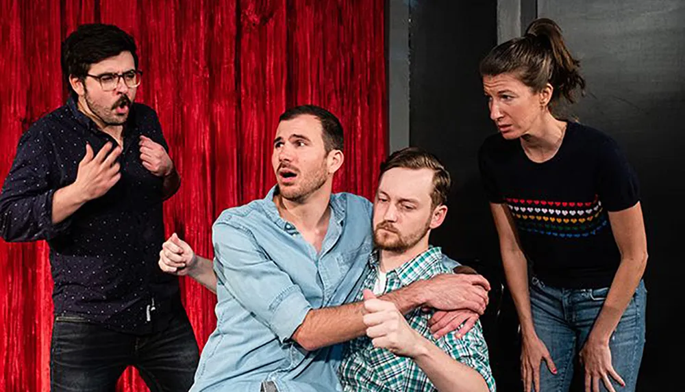 Four actors on stage display varying expressions of surprise and concern suggesting an emotional scene in a play or improvisational performance