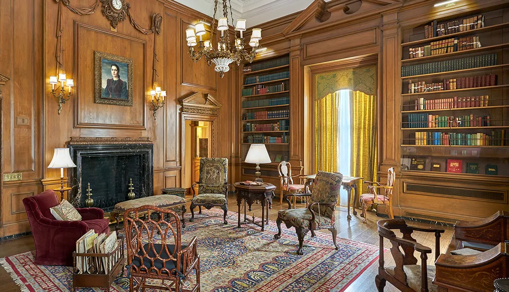 The image shows an elegant wood-paneled library room with a fireplace ornate furniture and shelves of books giving off a warm and classic ambiance