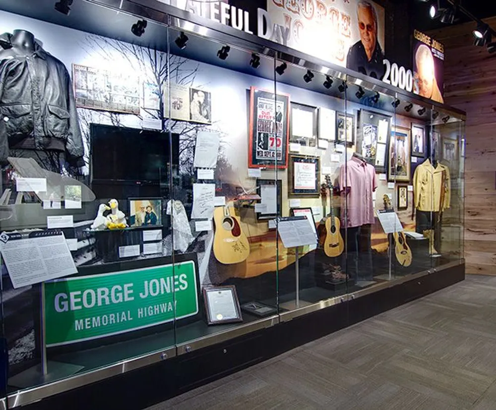 The image shows a museum display featuring memorabilia including guitars clothing and photographs dedicated to the legacy of a musician