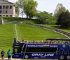 A couple is enjoying a scenic view from the top deck of a tour bus with a city skyline and a bridge in the background