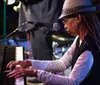 A musician in a cowboy hat is performing with an acoustic guitar on a stage singing into a microphone