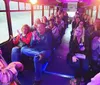 A group of people are sitting on a bus with purple lighting some smiling and clapping suggesting a lively atmosphere