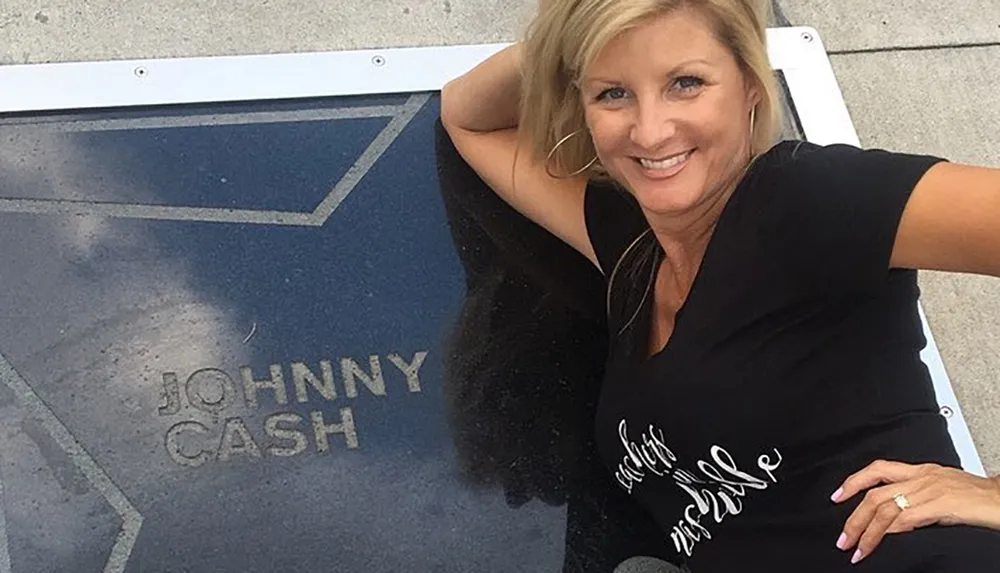 A smiling woman poses next to a star on a walkway that reads JOHNNY CASH