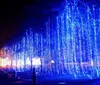 The image shows an illuminated snowflake-shaped decoration against a dusky or evening sky with a silhouette of trees in the background