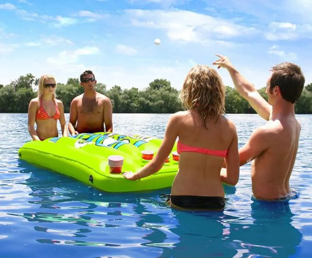 Four friends are enjoying a sunny day in the water with a floating game table