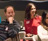 A woman is laughing heartily in a social setting with a logo reading The Dinner Detective visible in the background