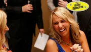 A woman is laughing heartily in a social setting with a logo reading