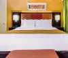 The image shows a colorful hotel room with two beds bright walls and modern decor