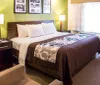 The image depicts a neatly arranged hotel room with a large bed side tables with lamps framed photographs on the wall and a sitting area all in a cohesive color scheme