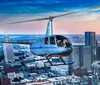 A helicopter is flying over a cityscape during twilight with buildings illuminated against a dusky sky