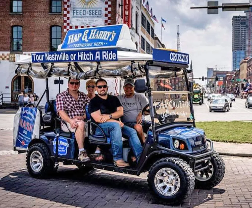 Four individuals are seated in an open-sided branded golf cart-like vehicle advertising tours and beer with an urban street scene in the background