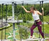 A person is navigating a rope course while wearing safety gear on a sunny day