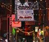 A group of people is gathered on a lively urban night street with neon signs and a sign for Korean Vets Bridge in the background