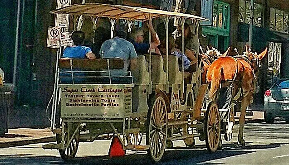 A horse-drawn carriage with passengers is strolling down an urban street