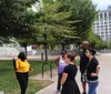 A group of people is standing on a sidewalk reading a historical marker titled Nashville Sit-Ins in an urban setting