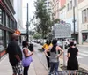 A group of people is standing on a sidewalk reading a historical marker titled Nashville Sit-Ins in an urban setting