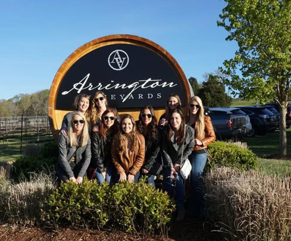 A group of friends poses for a photo in front of the Arrington Vineyards sign