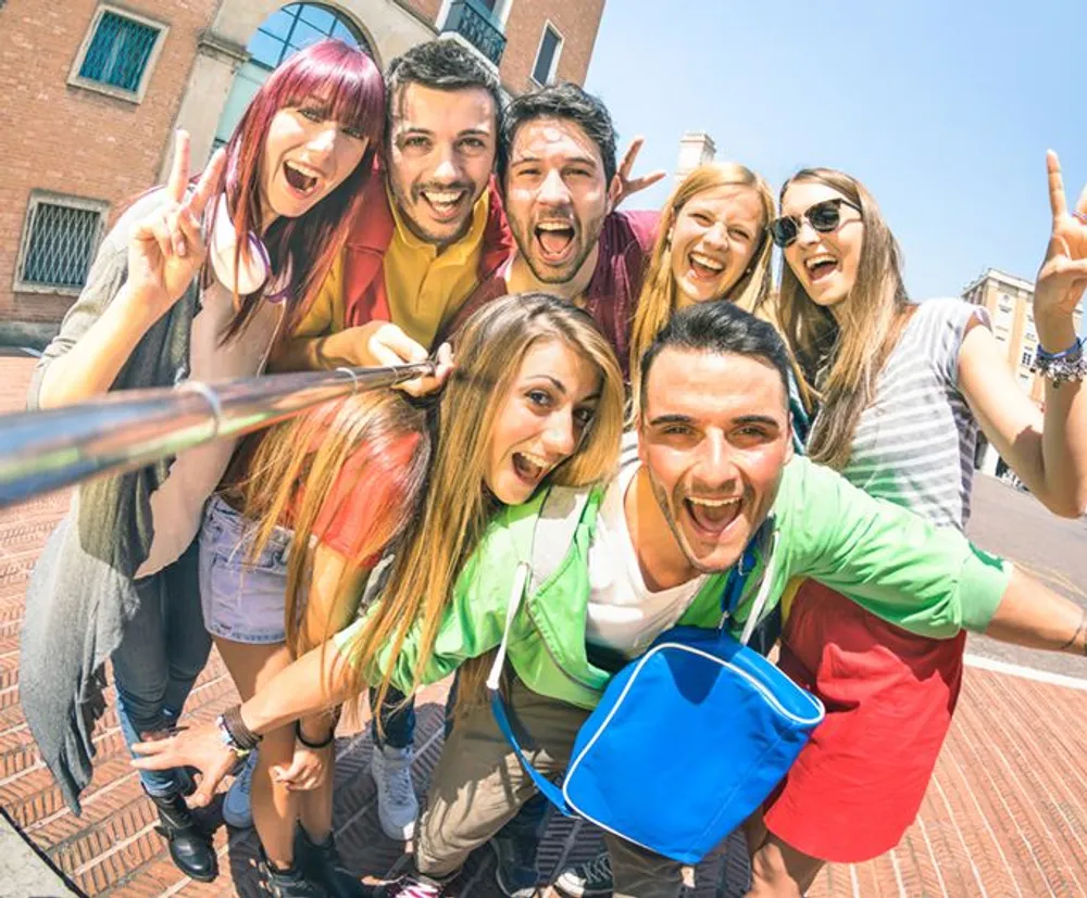 A group of cheerful young people are taking a selfie together on a sunny day