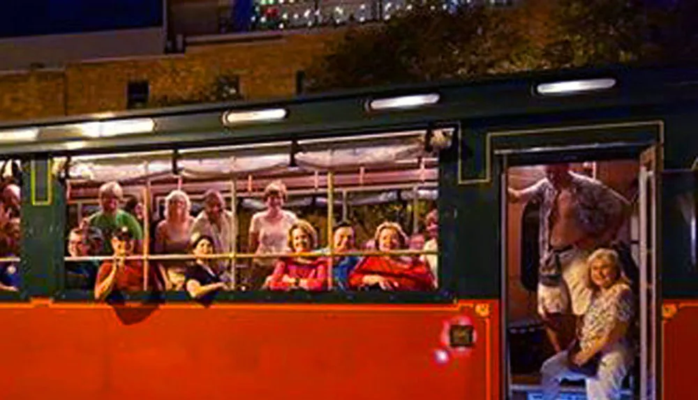 A group of people is enjoying a ride on an open-top tour bus at night