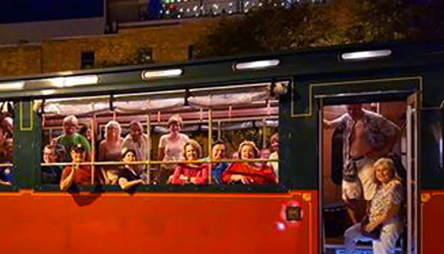 A group of people is enjoying a ride on an open-top tour bus at night.