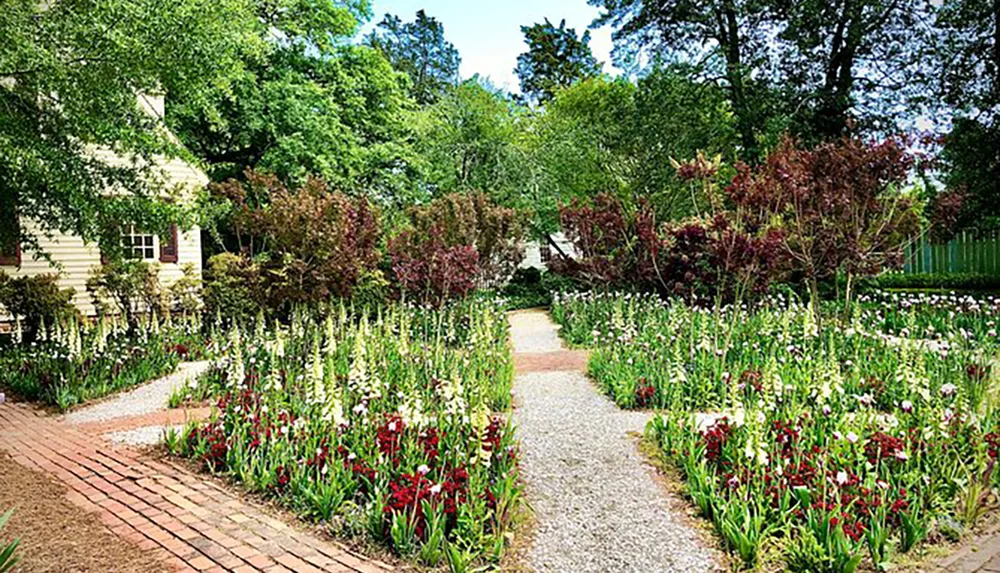 The image shows a serene garden pathway lined with vibrant flowers leading to a charming house among lush trees