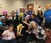 A cheerful group of people are posing for the camera many wearing fun animal-themed hats and making playful hand gestures