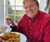 A cheerful person is enjoying a breakfast meal at a table by the window