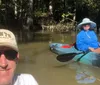 A person is kayaking under a bridge on a calm body of water wearing a life vest and actively paddling