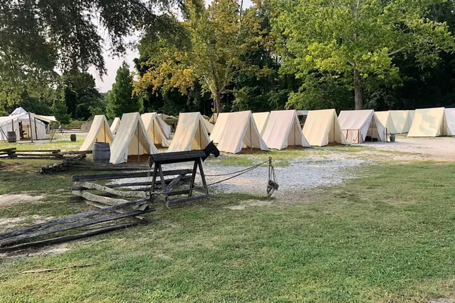 The image shows a row of canvas tents set up in a field, suggesting a historical reenactment camp or a living history museum.