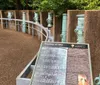 The image shows a curved walkway with a row of green cannons mounted on pedestals behind a metal barrier with an information plaque in the foreground titled Trophies of War