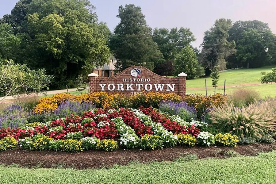 The image shows a well-maintained colorful flowerbed in front of a sign that reads Historic Yorktown 1781, suggesting a location of historical significance.