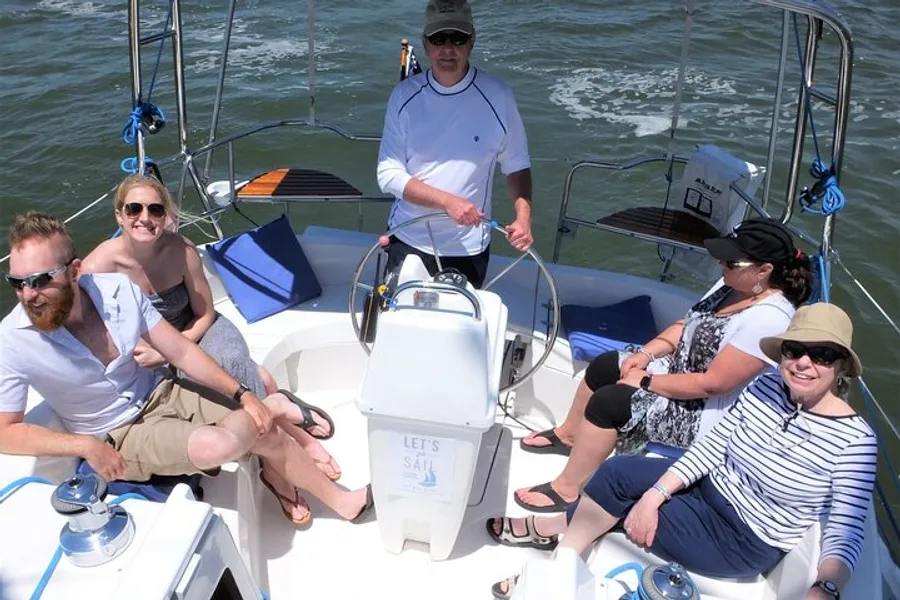 A group of people are smiling and enjoying a sunny day on a sailboat.