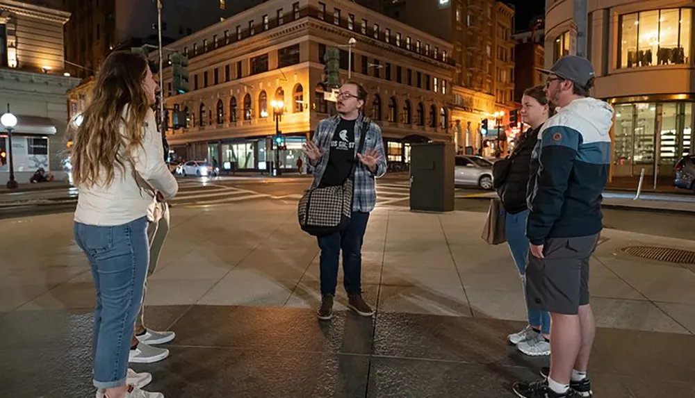 A group of individuals is engaging in a conversation on a city street at night likely part of a tour or social gathering