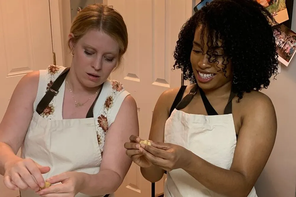 Two people are wearing aprons and engaging in a cooking activity with smiles focusing closely on their task