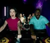 A group of excited and screaming riders are experiencing a thrilling moment on an indoor roller coaster with expressions of exhilaration and enjoyment under dim lighting