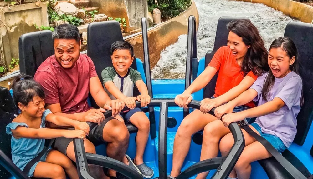 A family of five is joyfully riding a water ride holding onto the safety bars and laughing