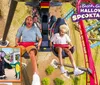 A group of excited and screaming riders are experiencing a thrilling moment on an indoor roller coaster with expressions of exhilaration and enjoyment under dim lighting