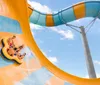 A group of people including children are enjoying a ride on a vibrant colorful water slide in a blue raft surrounded by sprays of water