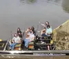 Three people wearing headphones are seated in a boat gliding on a river under a partly cloudy sky