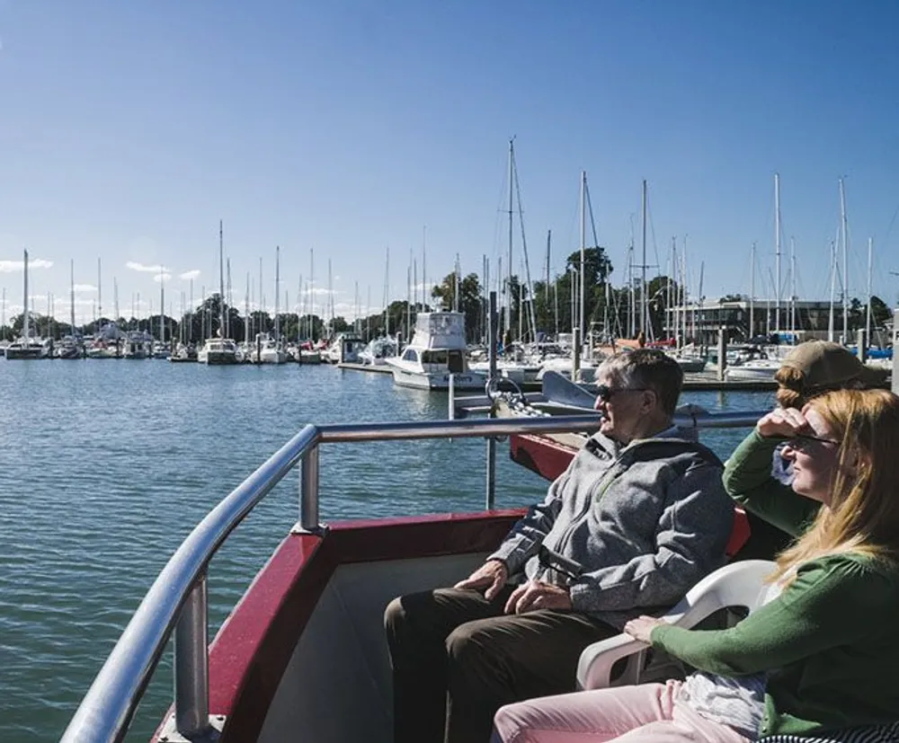 Two people are enjoying the sunny marina view from a boat