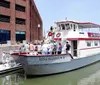 A tour boat named Miss Hampton II is cruising near a large naval aircraft carrier in a harbor