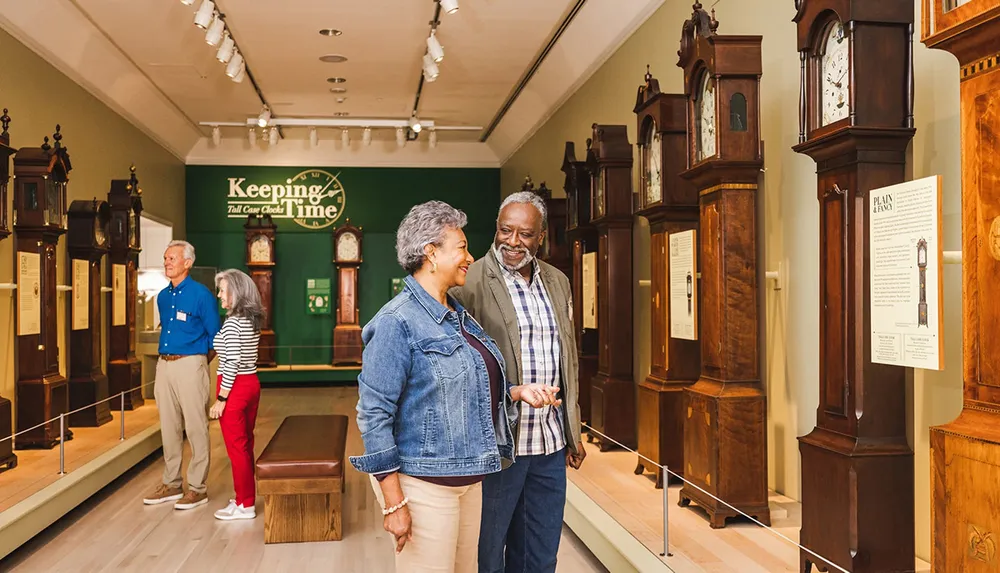 People are enjoying an exhibit of tall case clocks in a museum setting