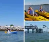 Two people in kayaks are paddling near an old lighthouse surrounded by a rocky breakwater under a clear blue sky