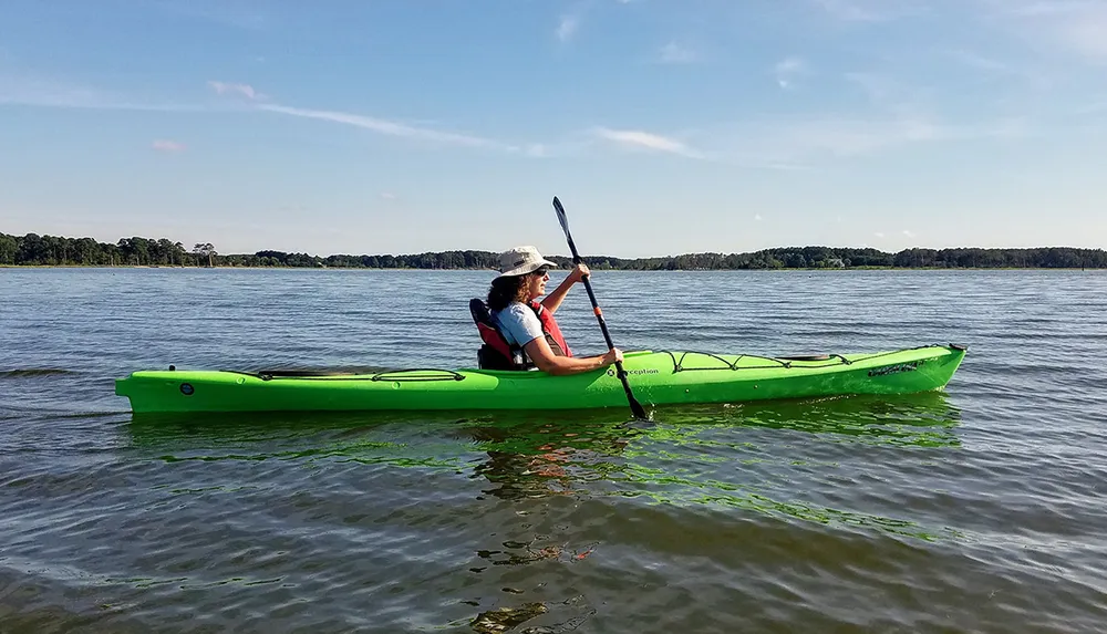 A person is kayaking on calm waters enjoying a sunny day