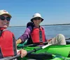 Two people are smiling while kayaking together on a sunny day