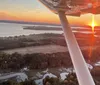 An aerial view from an airplane at sunset showcasing a vivid sky a reflective lake and the silhouette of the aircrafts wing