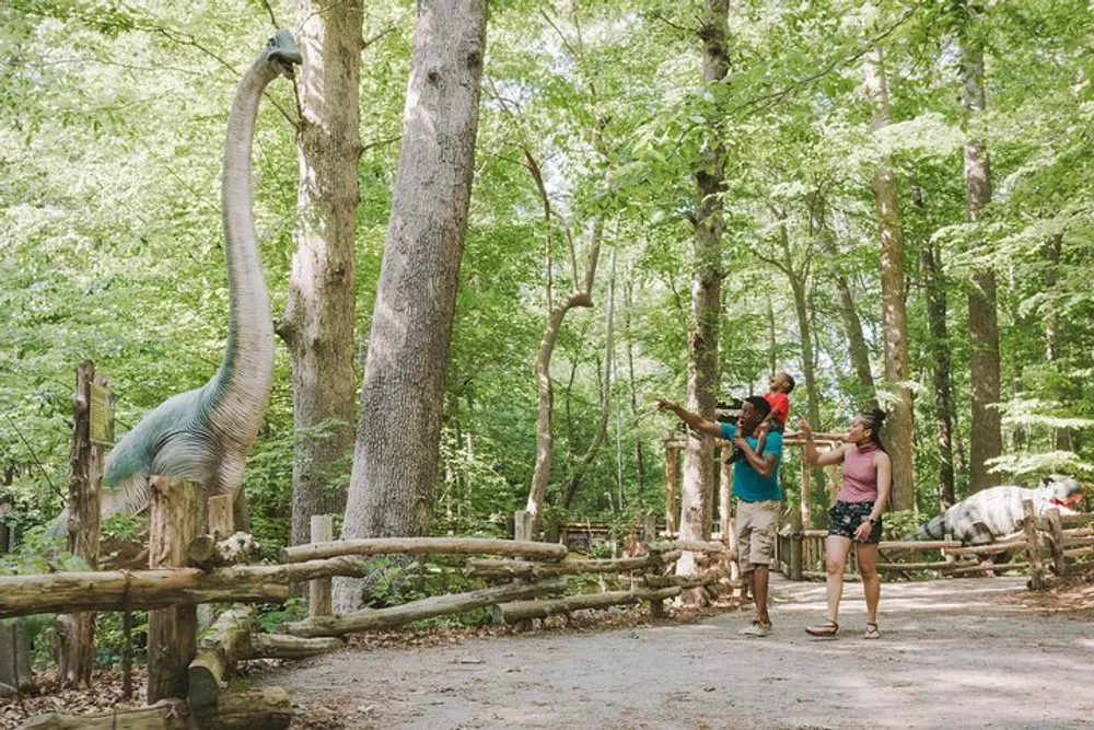 Two people are posing for a photo with a life-sized dinosaur sculpture at a park