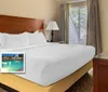 The image shows a hotel room with a large bed a nightstand with a lamp and windows promoting amenities like an on-site restaurant indoor pool playground and mini-golf with a Busch Gardens shuttle available